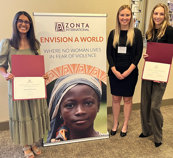 Three women with certificates beside Zonta banner.