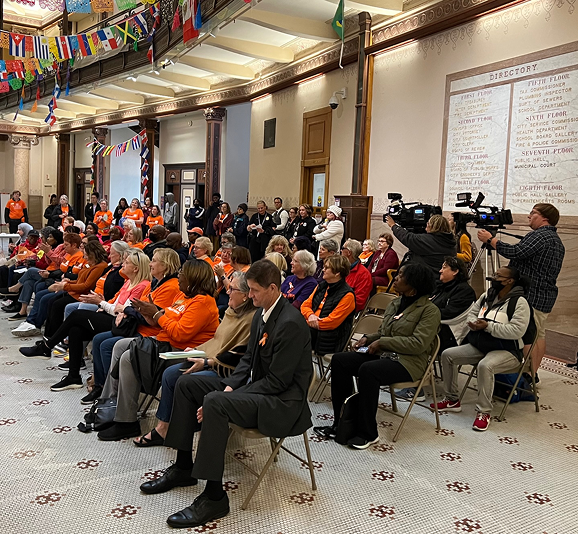 Audience seated in hall with cameras present.