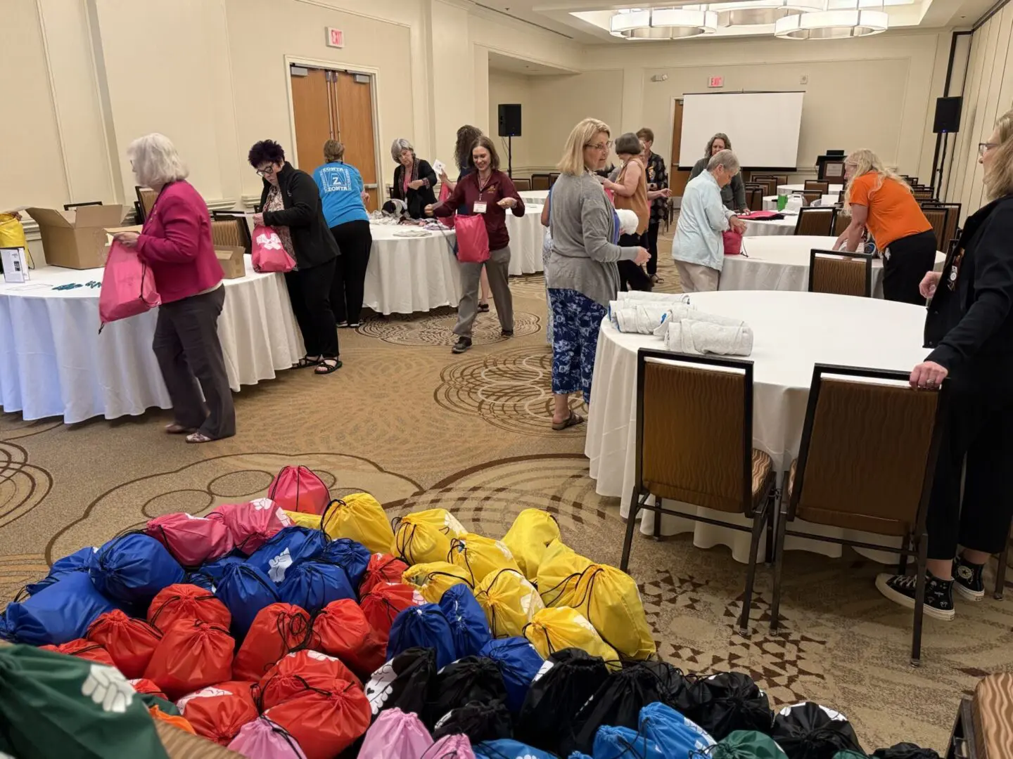 People packing colorful bags in conference room.