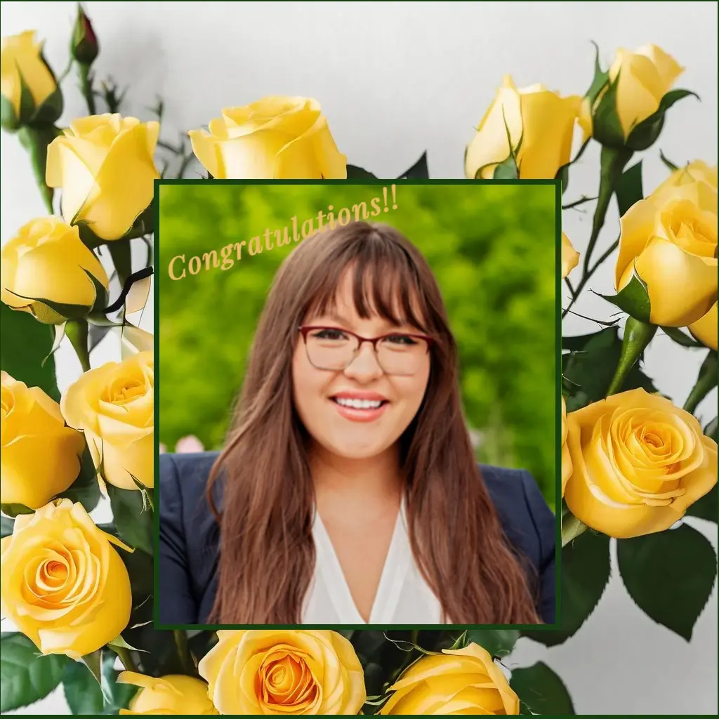 Portrait of a smiling woman with glasses framed by yellow roses.