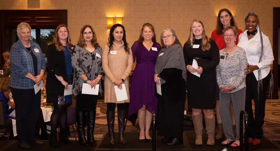 Group of women posing at a formal event with warm lighting.