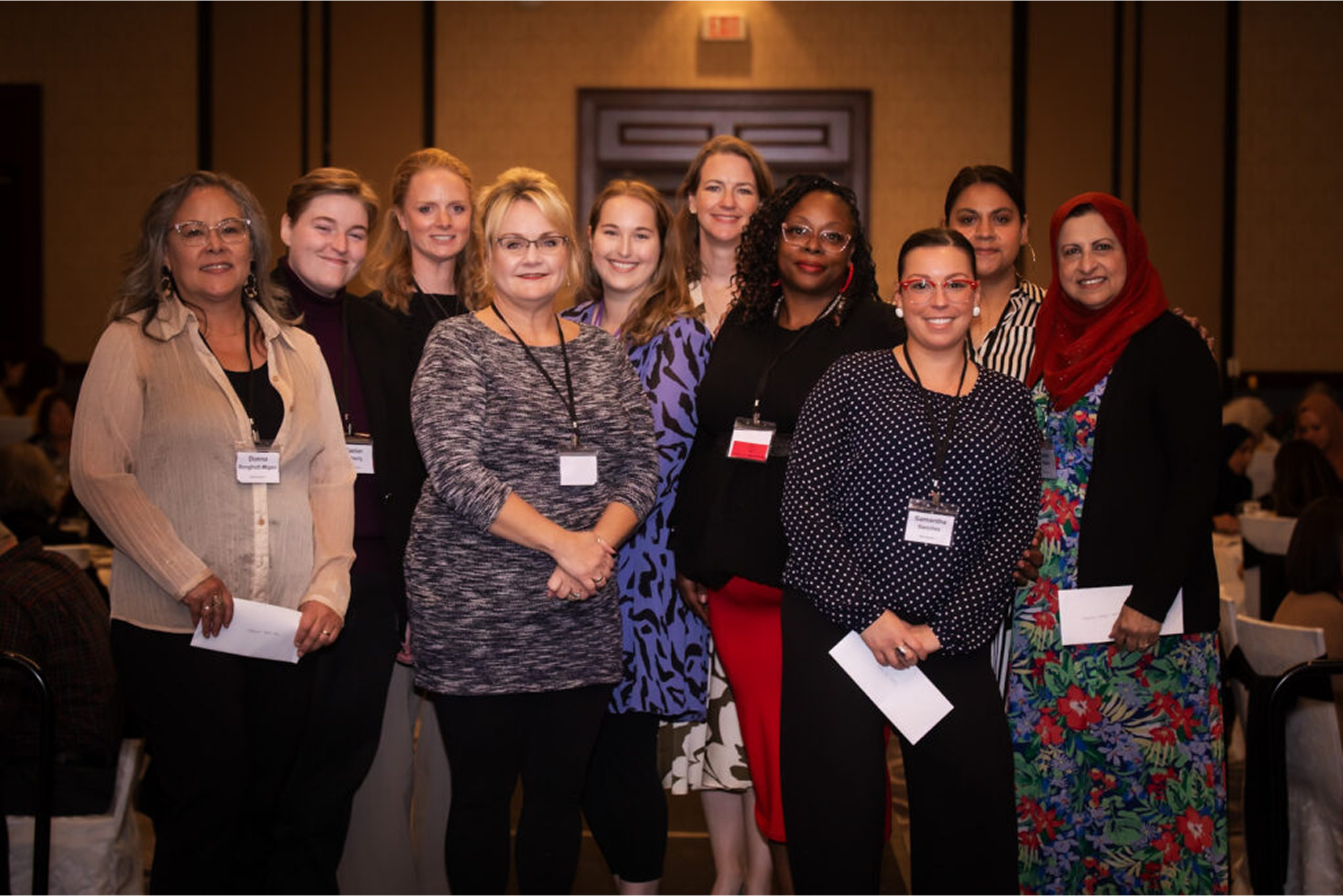 A diverse group of women smiling at a conference or event.
