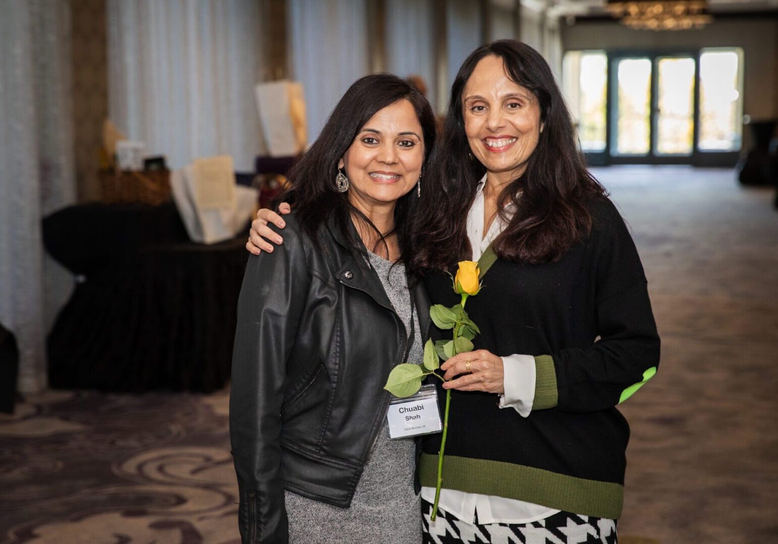 Two women smiling, one holding a rose.